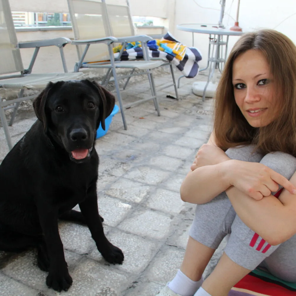Vlasnica sa crnim labradorom na terasi