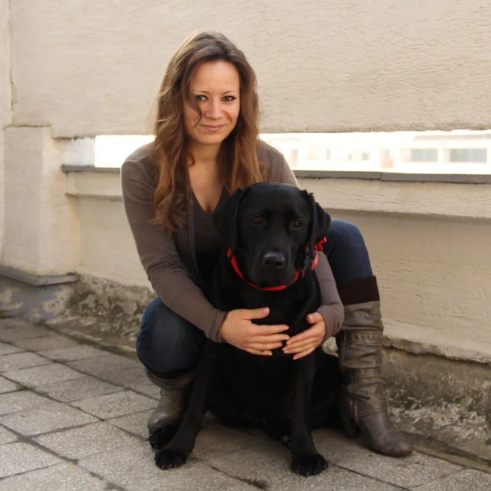 Vlasnica drži crnog labradora na terasi